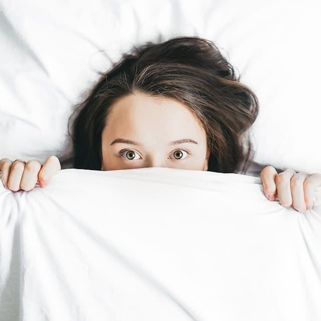 A girl hiding her mouth tape with a blanket